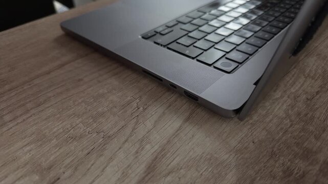 Close up of hands typing on a laptop then unplugging a USB C cable.