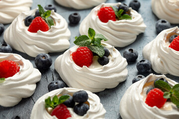 Meringue nests, mini pavlova cake with cream, fresh berries, blueberry, raspberry and mint for healthy desert.
