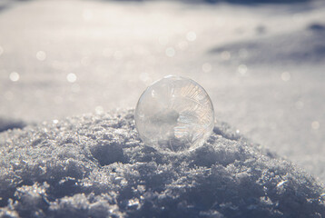 A frozen bubble full of flower-like ice crystals outdoors during winter, made with sugar, water and dishwashing liquid.