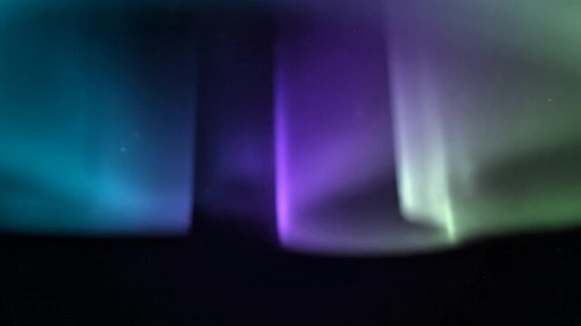 Cinematic wide shot of the Northern Lights dancing across the dark night sky