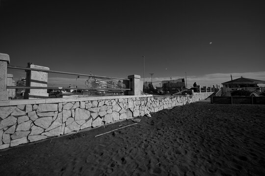 Ostia, Rome, Italy - January 25, 2026, section of a travertine retaining wall in opus incertum with perspective view of a stretch of public beach near the Hakuna Matata kiosk.