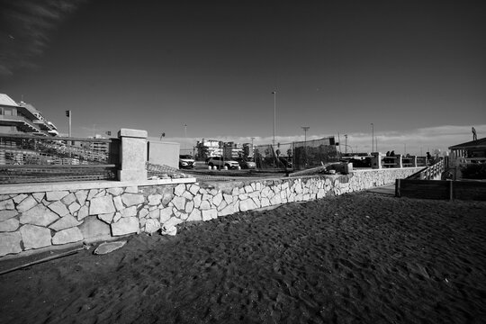 Ostia, Rome, Italy - January 25, 2026, section of a travertine retaining wall in opus incertum with perspective view of a stretch of public beach near the Hakuna Matata kiosk.