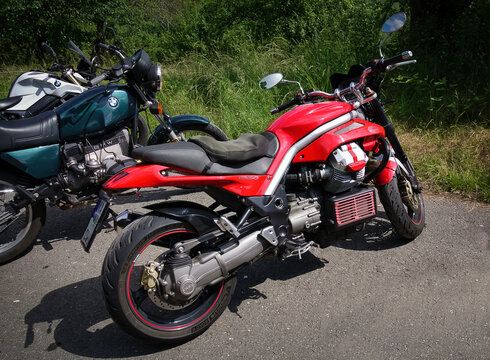 Eine rote Moto Guzzi Griso neben zwei Motorr&auml;dern der Marke BMW geparkt