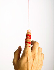 Finger Pulling Red Thread on White Background
赤い糸を引く指のクローズアップ
