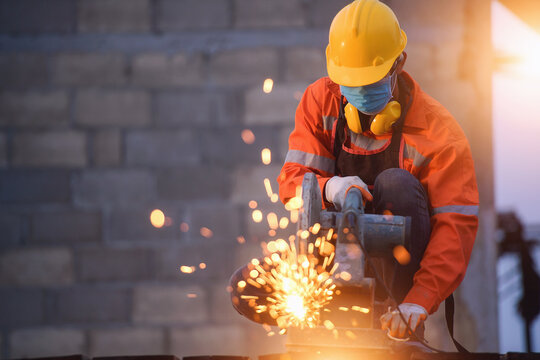 Construction working wearing protective workwear standing in a new build building using a circular saw