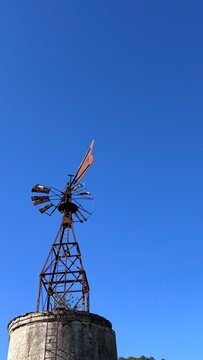 Traditional weathered metal windpump windmill on a stone tower, France