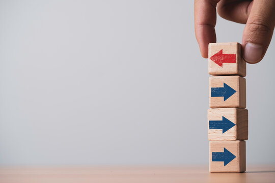 Hand change direction of wooden red arrow blocks for showing disruption change for business transformation and technology innovation shift concept.