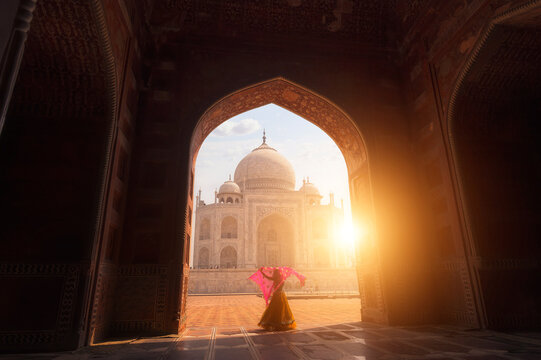 Rear view of a Young Woman in a sari standing in front of the Taj Mahal holding a shawl above her head at sunset, Agra, Uttar Pradesh, India,