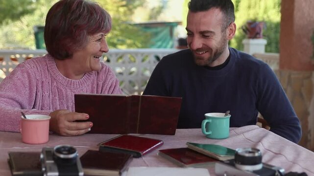 Mother and son looking at a photo album and reliving precious moments. Nostalgia concept