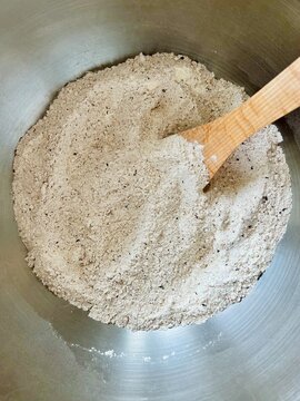 Close-up overhead view of assorted types of flour mixed together in a metal bowl