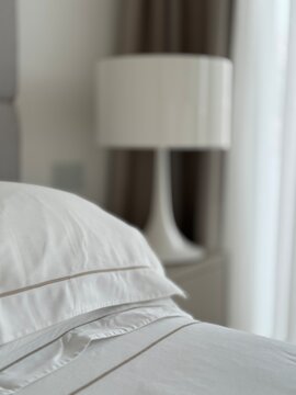 Luxury white cotton bedding on a bed with a lamp on a bedside table
