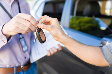 Closeup of driving instructor handing car keys to adult learner after lesson, emphasizing...