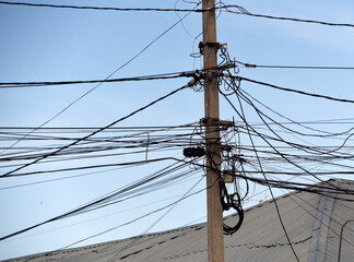Strommast mit maroden Leitungen vor blauem Himmel