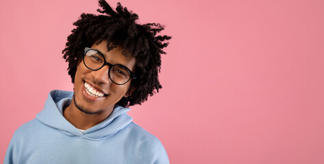 Portrait of handsome black teenager in casual clothes smiling and looking at camera over pink...