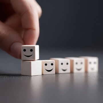 Hand choosing smile face from emotion blocks, positive feedback and satisfaction survey concept