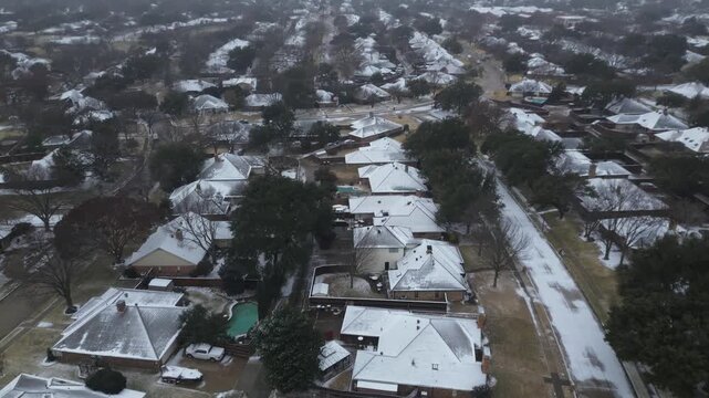 Homes in Dallas Fort Worth metroplex exhibit icy rooftops and slick driveways from Winter Storm Fern, leafless trees, backyard pools punctuating winter stillness. Subtle shadows, Coppell, Texas