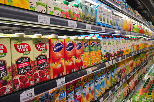 Penang, Malaysia: Nov 06, 2025: Rows of various fruit juice cartons including F&N Fruit Tree Fresh, Sunkist Apple, and Marigold Peel Fresh displayed in a commercial cooling unit at a grocery store.