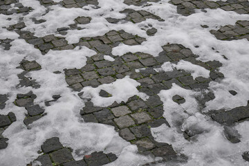 Melting Snow on Dark Gray Cobblestone Pavement