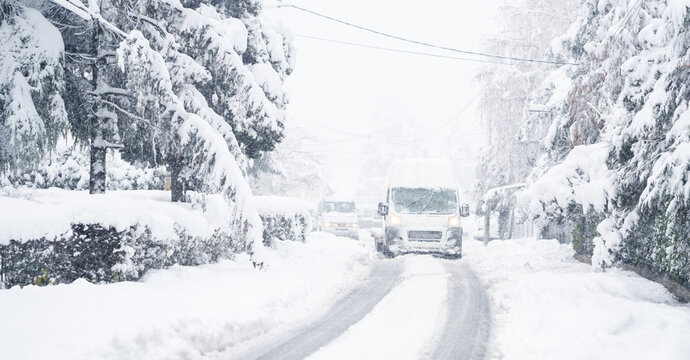 Delivery van on a snow covered winter road during snowstorm