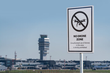 Sign NO DRONE ZONE with airport terminal in a backgroun