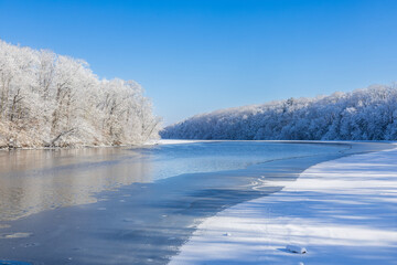 Semi-frozen lake surrounded by snow-covered trees