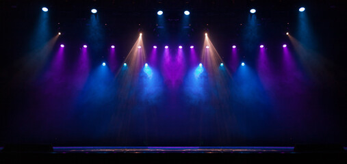 An empty stage of the theater, lit by spotlights and smoke before the performance