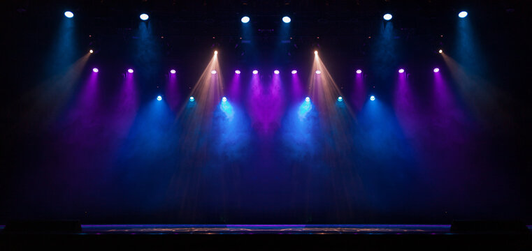 An empty stage of the theater, lit by spotlights and smoke before the performance
