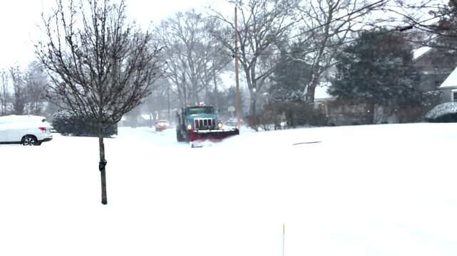 Two Snowplows Clearing a Residential Street Early during a Snow Storm