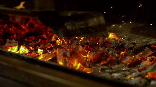 spreading embers in the fireplace before barbecuing
