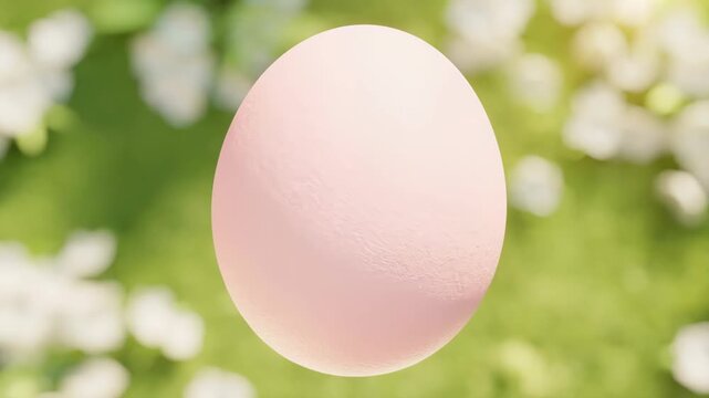 Single pastel pink Easter egg with soft texture on blooming spring background, top view, slow rotation video footage