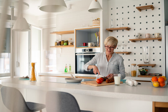 Senior woman preparing a healthy meal in a bright modern kitchen with natural morning light