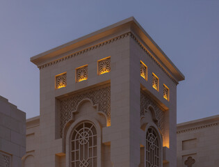 Fototapeta premium Evening view, illuminated eastern buildings. Architectural elements of buildings, ancient arches and columns. On the streets of the Emirates, in public spaces.