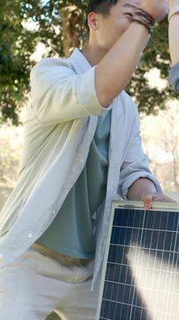 Vertical video: Holding solar panel man in shirt showing friend approaching and highfiving in yard