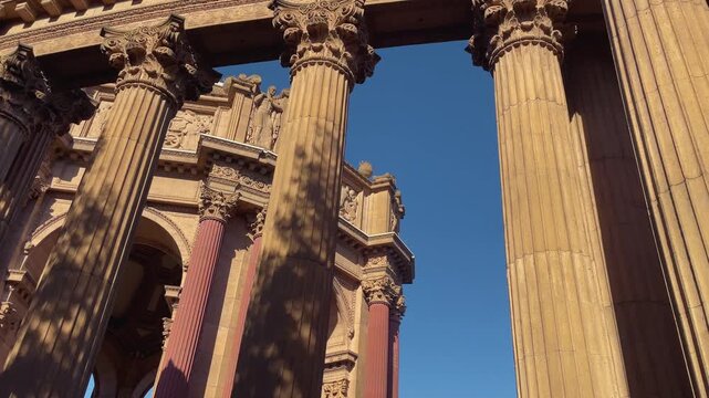 Handheld 4K tilt up shot revealing the majestic neoclassical dome of the Palace of Fine Arts in San Francisco California at sunset Iconic architectural landmark under a clear blue sky during dusk