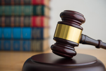 Judge gavel hammer on wooden table with law textbooks background. Law, legislation, justice, enforcement, law education and so on concept.