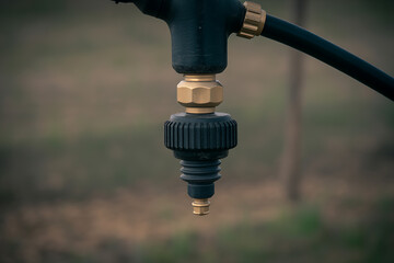Detail of a hose fitting with brass and black components, connected to a pipe, symbolizing fluid transfer and irrigation systems.