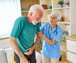 Fototapeta premium Doctor or nurse caregiver helping senior man holding walking cane at home or nursing home