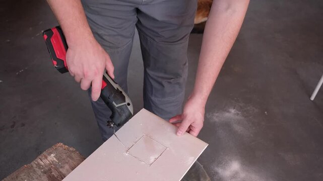 Male hands with oscilliating multi-tool cutting plaster board