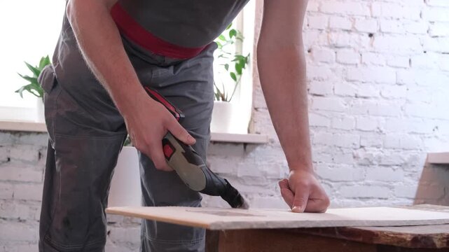 Male hands with renovator oscilliating multi-tool cutting plaster board