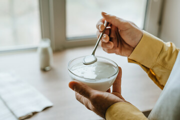 Close-up of man wearing a yellow shirt and an apron holding yogurt in a bowl