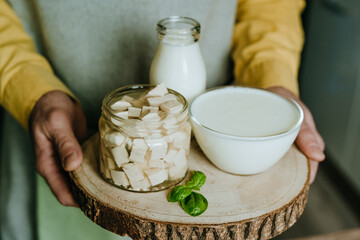 Close up of male hands holding wooden tray with tofu, yogurt and milk