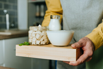 Close up of man holding wooden tray with tofu, yogurt and milk
