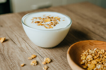 Yogurt with granola in a bowl on wooden background