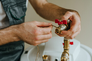 Worker's hands wrapping hemp sealing thread around a metal fitting