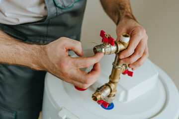 Worker's hands applying waterproofing paste around a metal fitting on a water heater