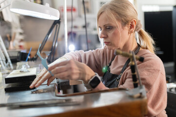 Woman crafting jewelry in workshop using tools