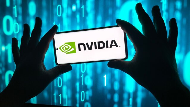Hands hold smartphone displaying nvidia logo against binary code
