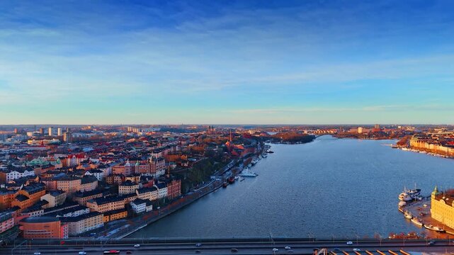 Flight over the riverscape crossing the cityscape of Stockholm, Sweden. Sunset light colors the panorama of one city side.