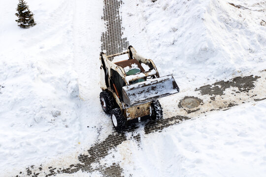 Tractor working diligently to clear winter snow and ice from residential streets
