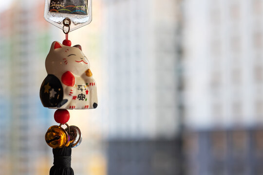 Ceramic lucky cat with charms, Small ceramic charm featuring bells and tassels by window